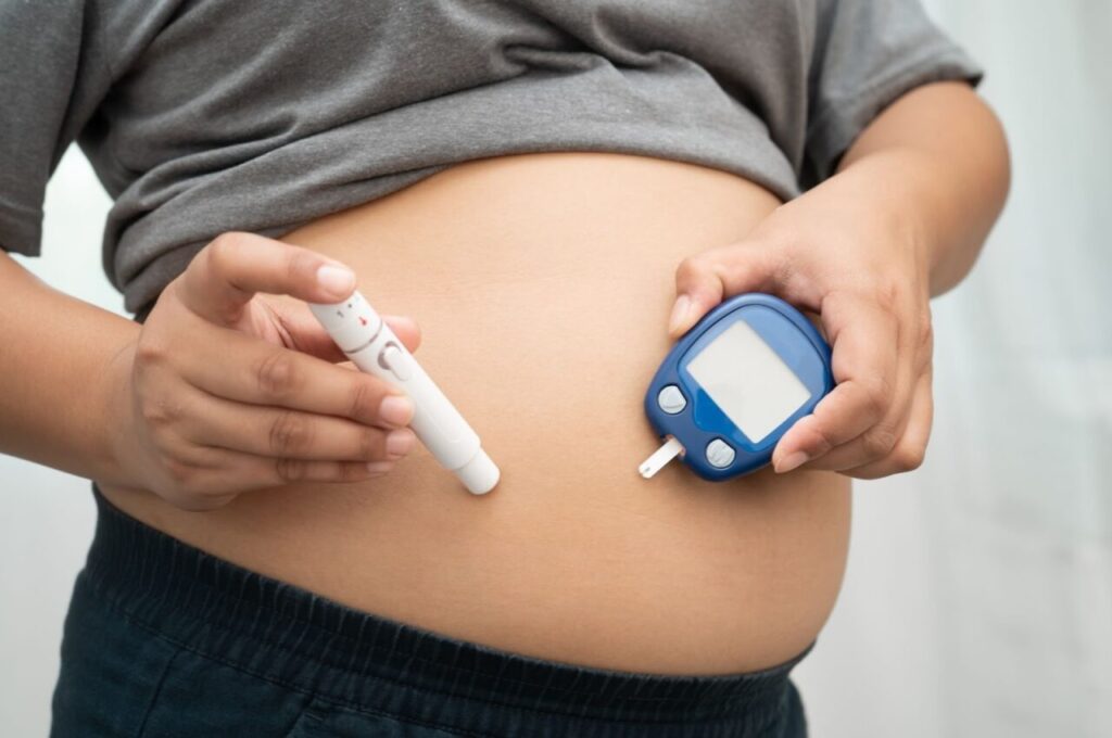 血糖値測定器と注射薬をお腹に注射している太った人