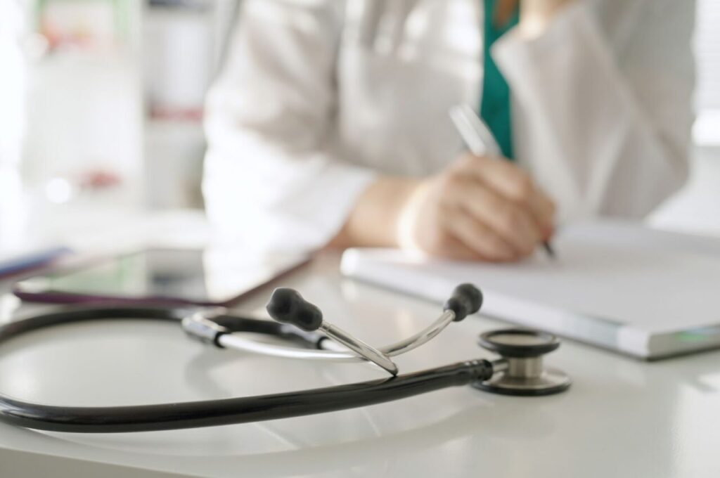 紙に書き込んでいる医師と聴診器