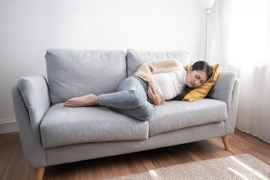 お腹を押さえてソファに横になっている女性