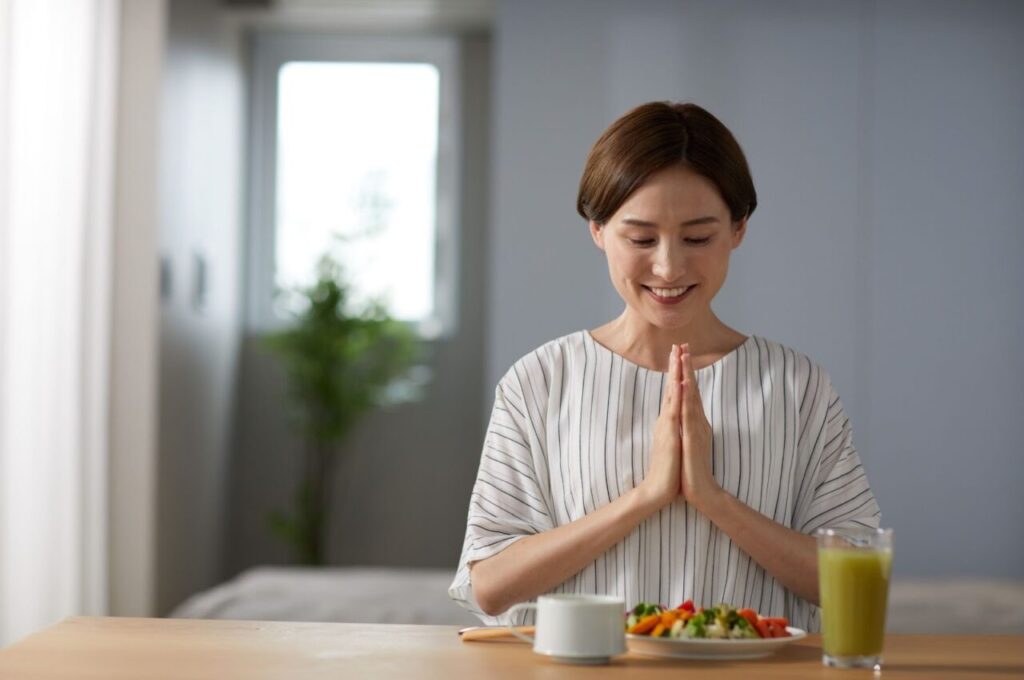 栄養バランスのいい食事を前に手を合わせている女性