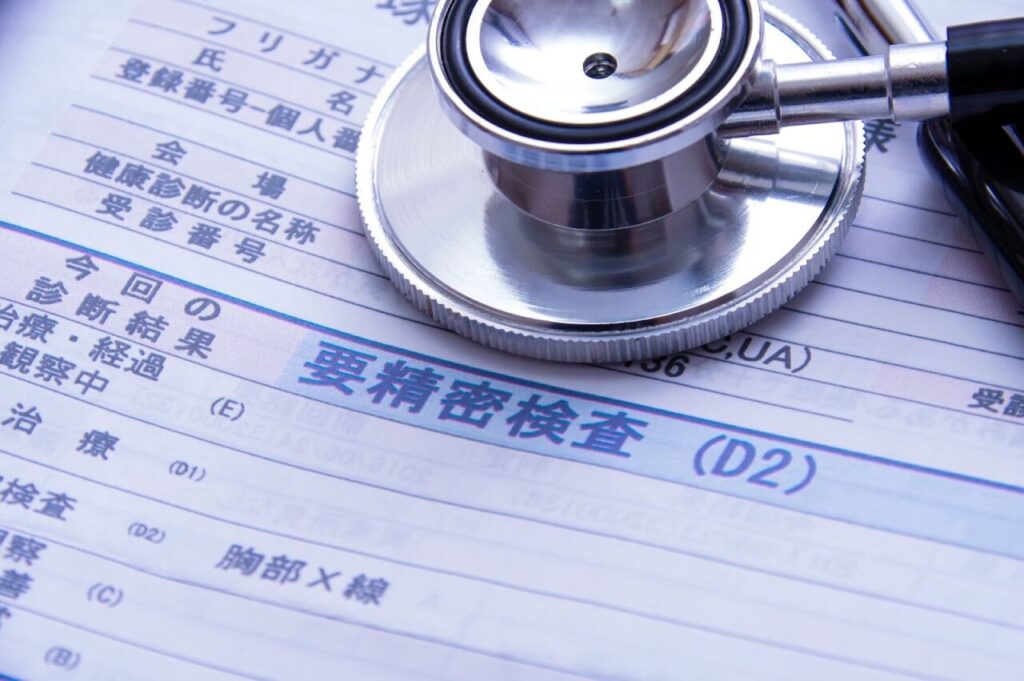 要精密検査と書かれた検査結果用紙と聴診器