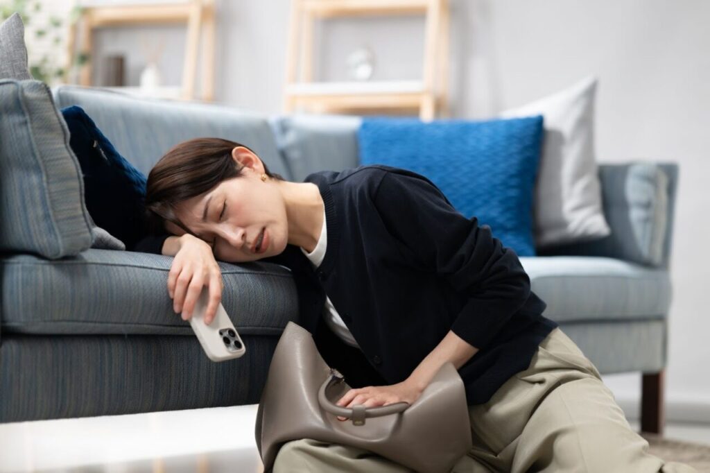 体調不良でソファにもたれかかる女性