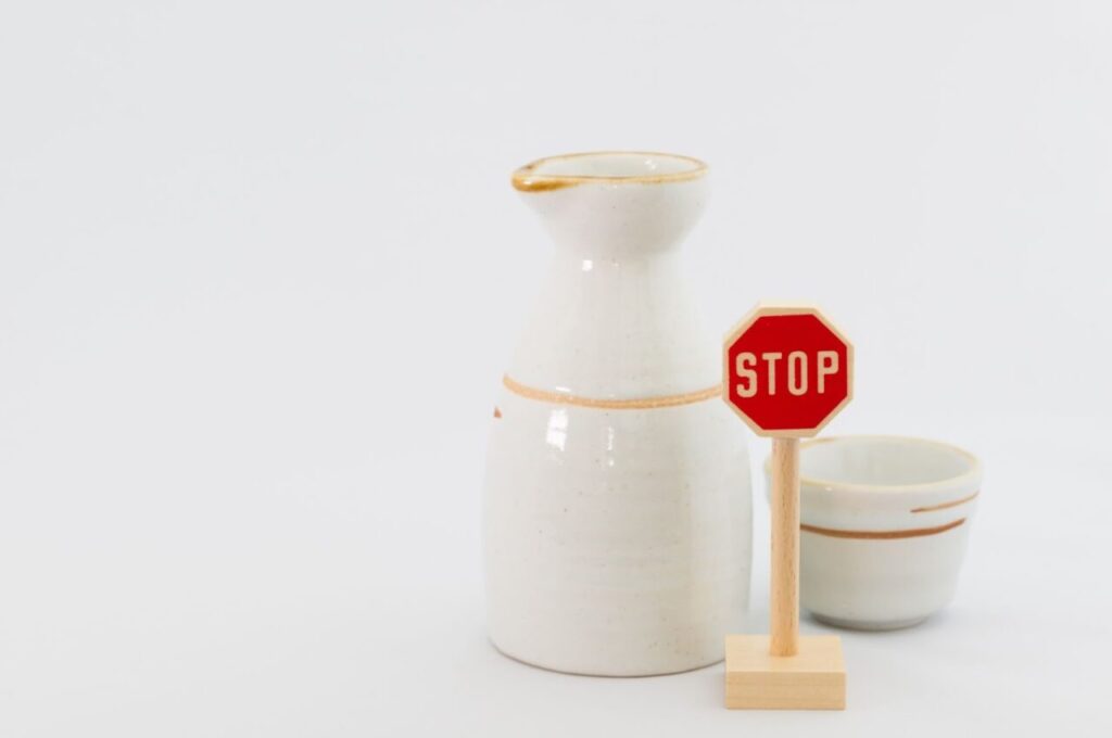 日本酒の徳利とお猪口とSTOPと書かれた小さな標識