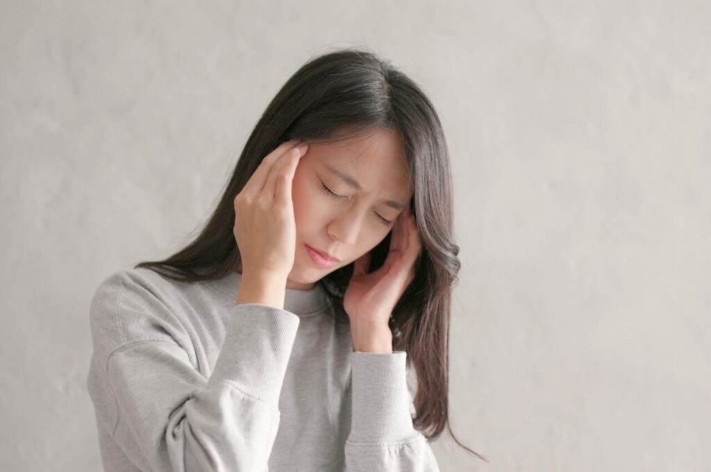 高血圧による頭痛でつらそうな女性
